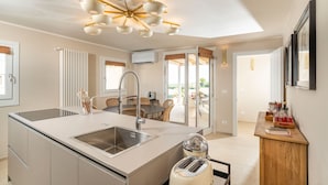 A modern kitchen with a central island, a built-in sink, and a ceiling fan. - Exclusive property with terrace and plunge-pool, Noto, Sicily (Noto)