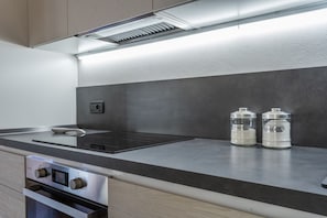 Eine moderne Küche mit einem eingebauten Backofen, einem Kochfeld und zwei Salzstreuern auf der Arbeitsfläche.