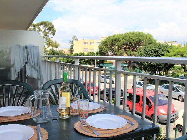 Ein Balkon mit einem Tisch für zwei Personen, gedeckt mit Tellern, Besteck, einer Karaffe und einer Weinflasche.