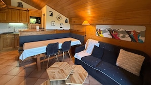 Acogedor interior de cabaña con comedor, paredes de madera y sofá.