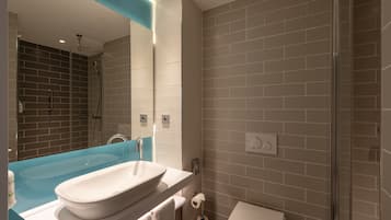 A modern bathroom with a large white sink, a glass-enclosed shower, and a white toilet.