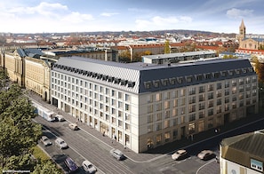 A modern building with a flat roof and large windows, surrounded by a cityscape with a prominent tower in the background. - Holiday Inn Express and Suites Potsdam by IHG (Potsdam)