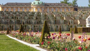 A large, ornate building with a green dome and symmetrical architecture, surrounded by a well-maintained garden with various flowers and trimmed hedges. - Holiday Inn Express and Suites Potsdam by IHG (Potsdam)