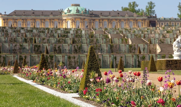 A large, ornate building with a green dome and symmetrical architecture, surrounded by a well-maintained garden with various flowers and trimmed hedges. - Holiday Inn Express and Suites Potsdam by IHG (Potsdam)