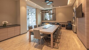 A modern dining area with a long table, chairs, and a kitchen counter. - Holiday Inn Express and Suites Potsdam by IHG (Potsdam)