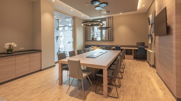A modern dining area with a long table, chairs, and a kitchen counter. - Holiday Inn Express and Suites Potsdam by IHG (Potsdam)