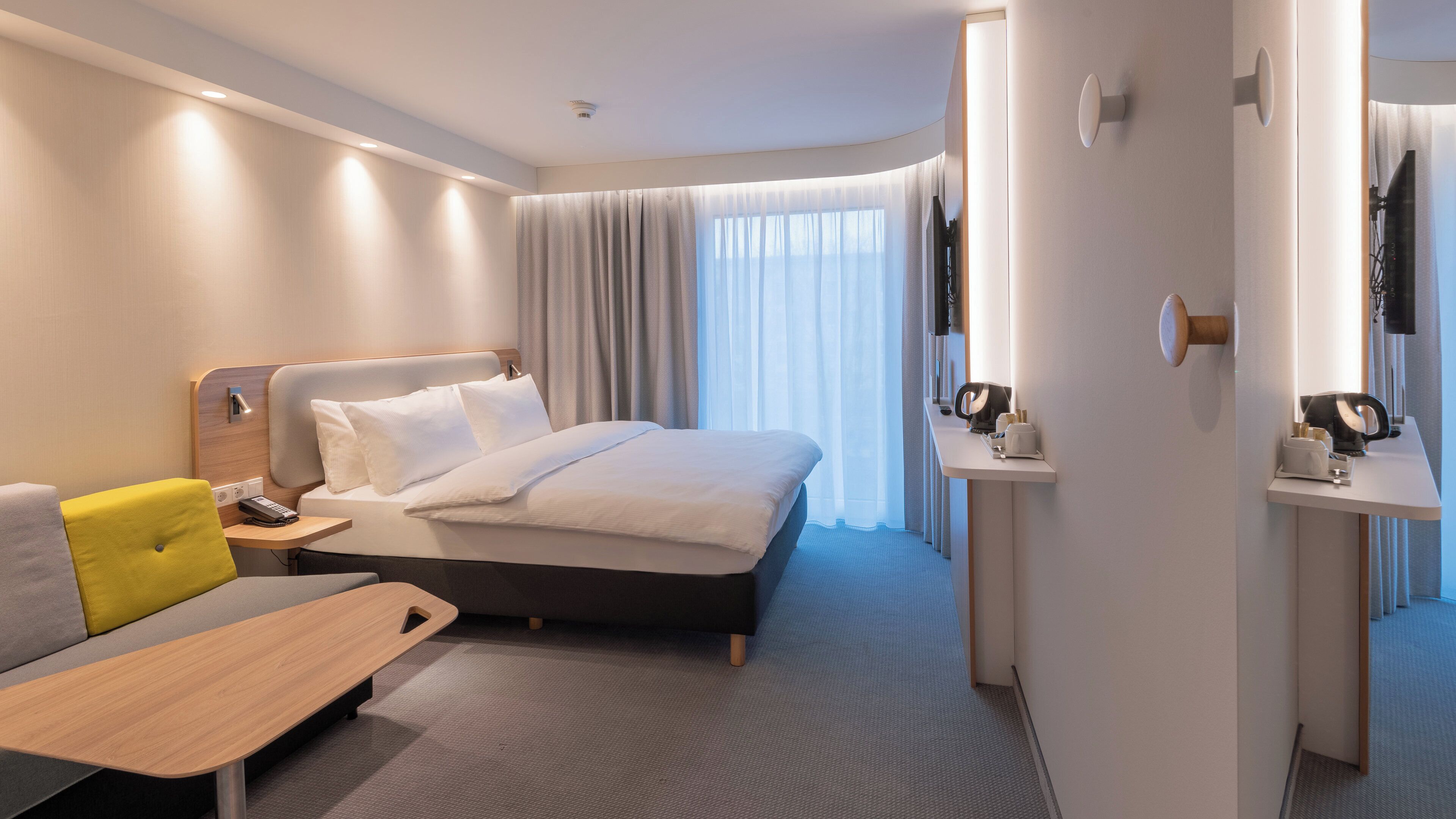 Une chambre d’hôtel moderne équipée d’un lit, d’un bureau, d’une chaise et d’une petite table.