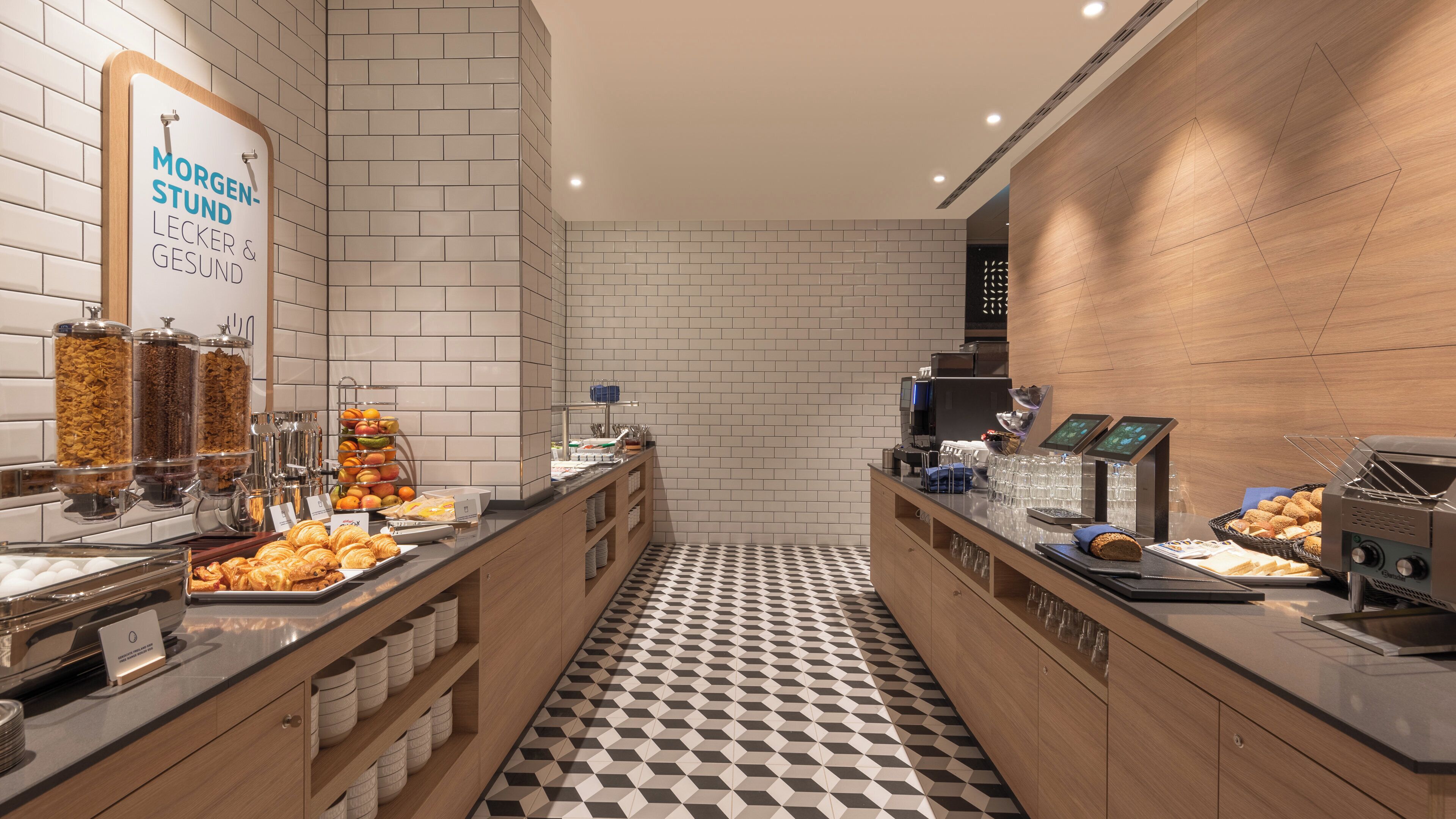 A breakfast buffet area with various food options, including fruits, pastries, and cereals.