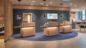 A hotel reception area with three reception desks, a large sign for Holiday Inn Express & Suites, and a counter with a coffee machine. - Holiday Inn Express and Suites Potsdam by IHG (Potsdam)