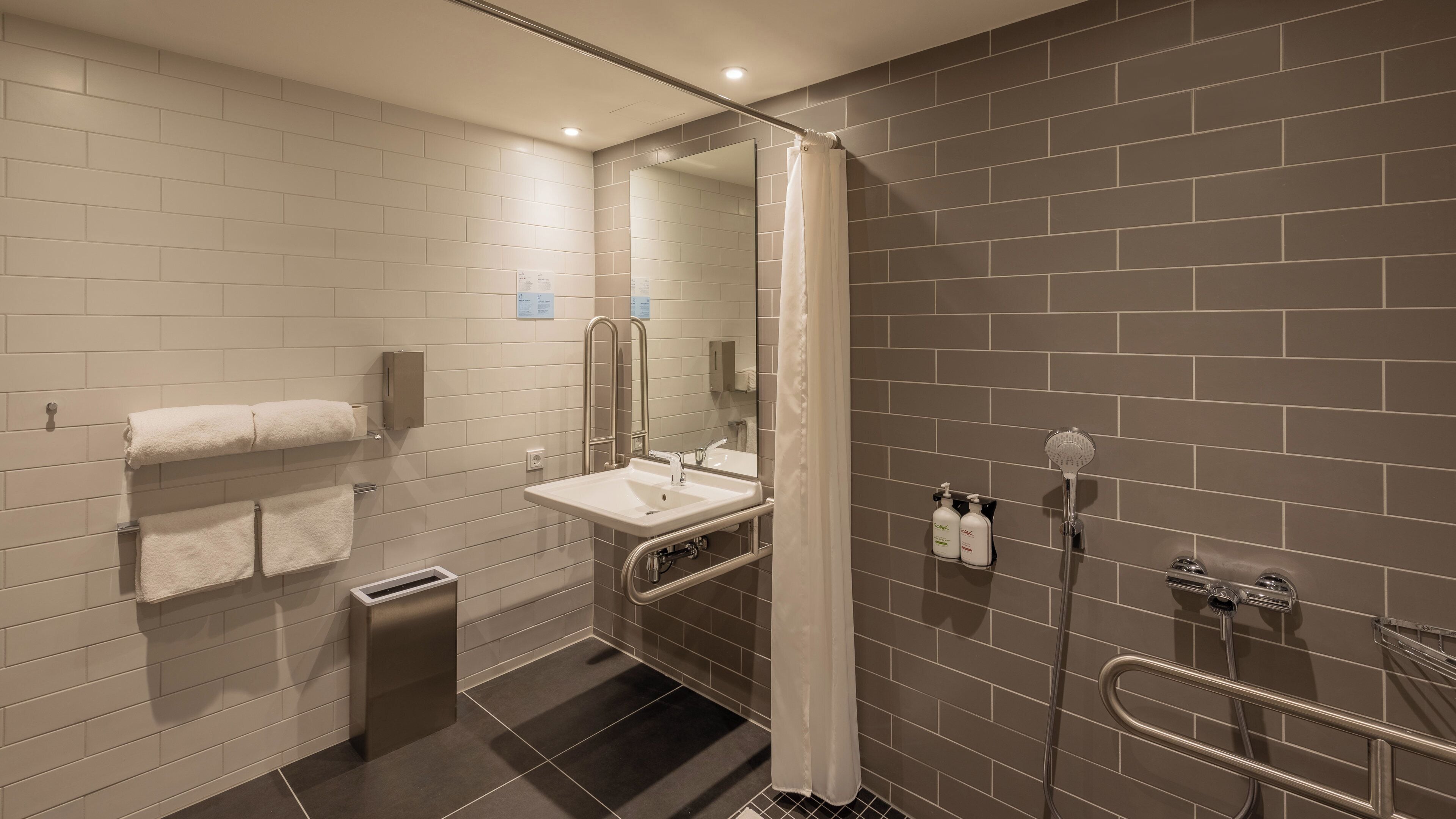 A modern bathroom with a white sink, mirror, and towel rack.