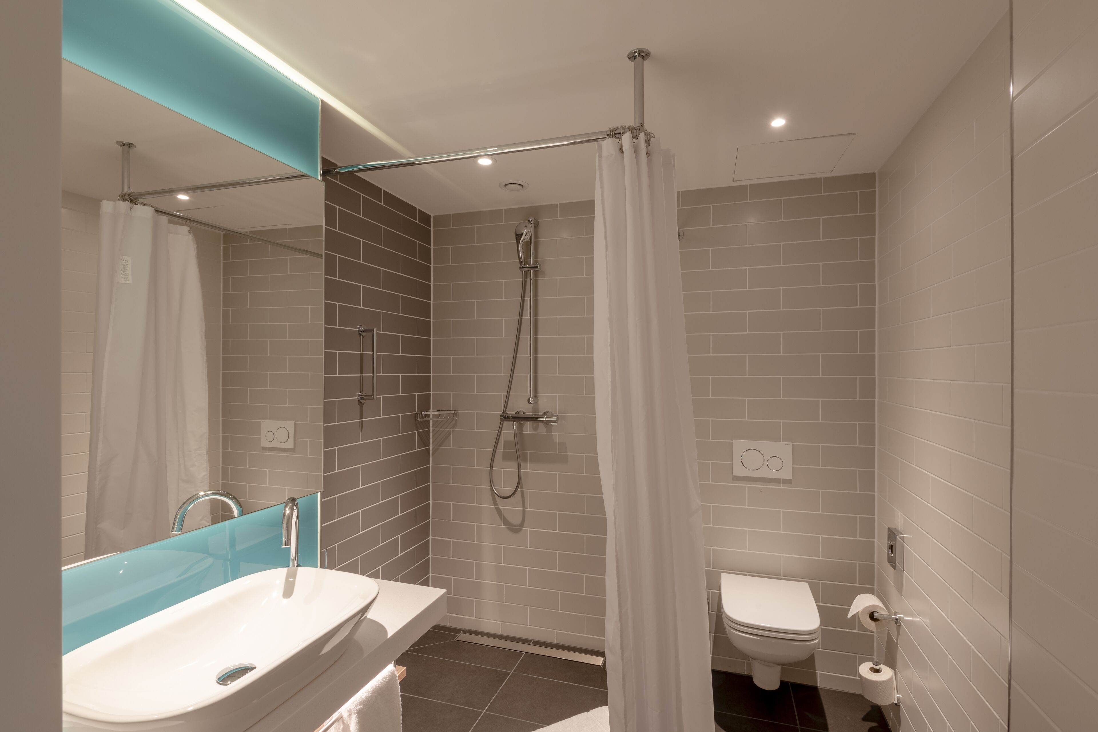 A modern bathroom with a glass-enclosed shower, a white sink, and a toilet.