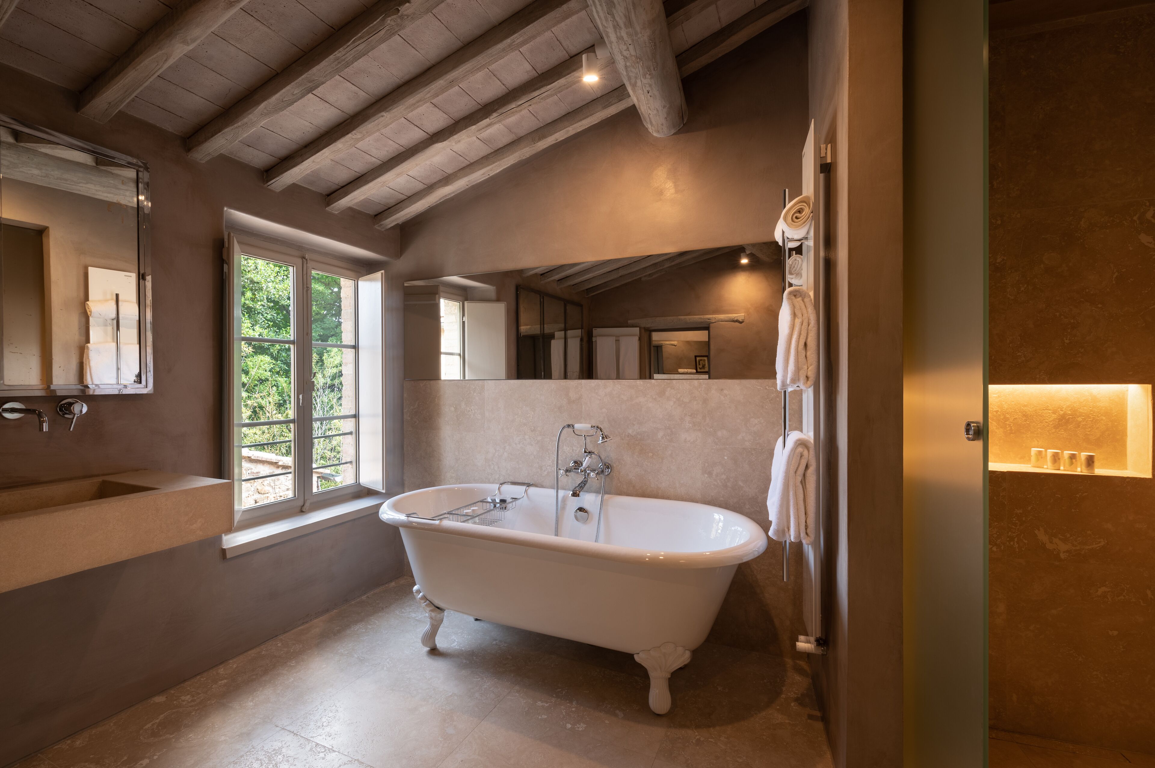 Une salle de bain avec une baignoire sur pieds, une grande fenêtre et un miroir.