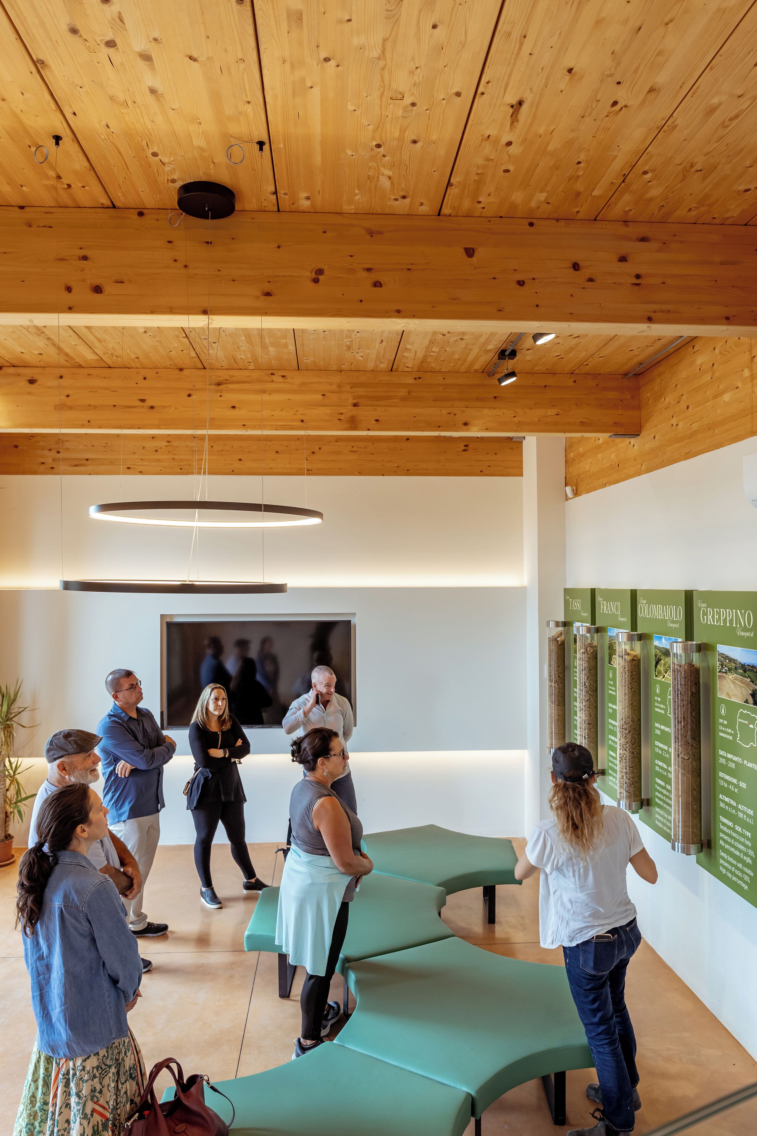 Un interior moderno con techos de madera, asientos verdes y paneles informativos.