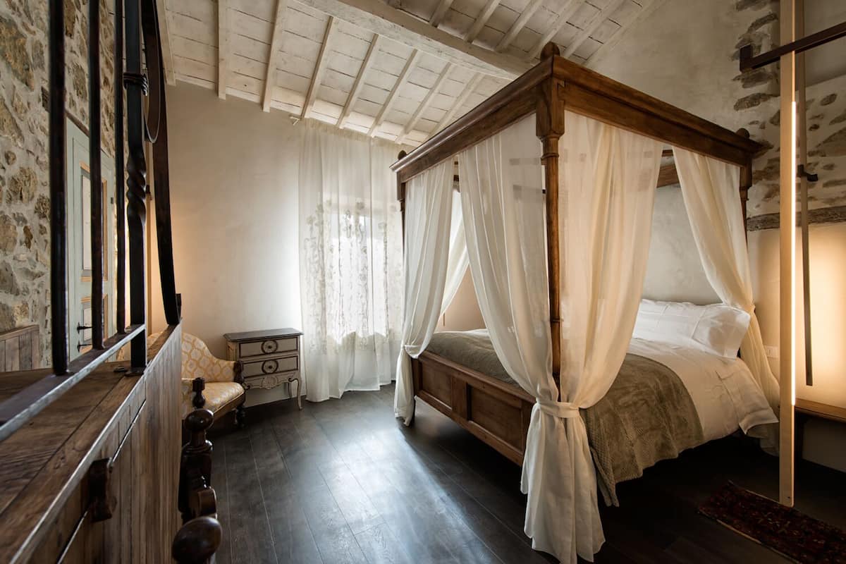 Un dormitorio con una cama con dosel, una mesita de noche de madera y un tocador pequeño.