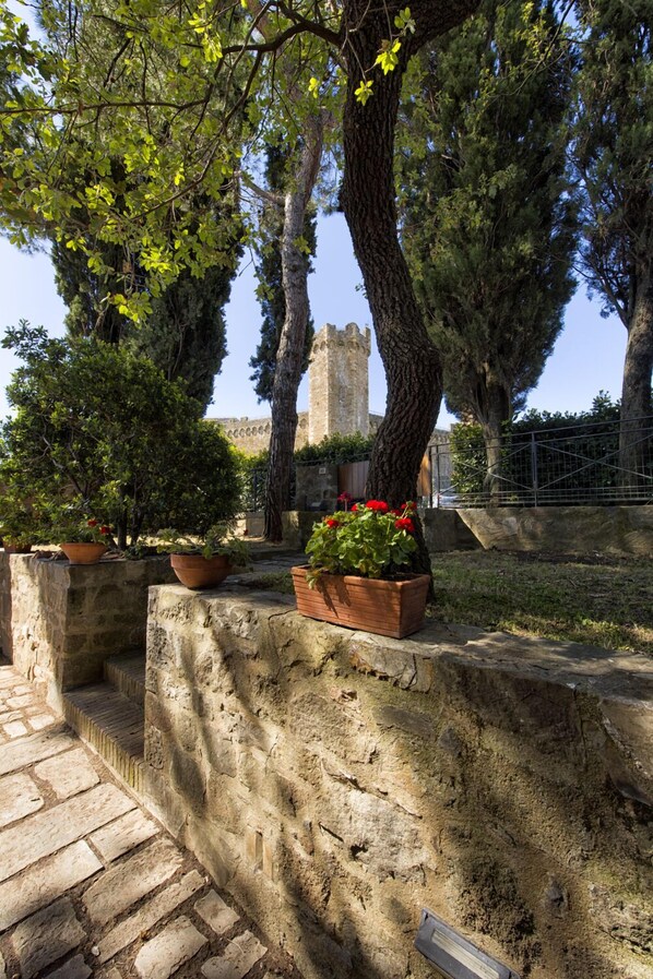 A stone pathway leading to a courtyard with potted plants and a view of a historic tower. - Casa Franci Montalcino  (Montalcino)