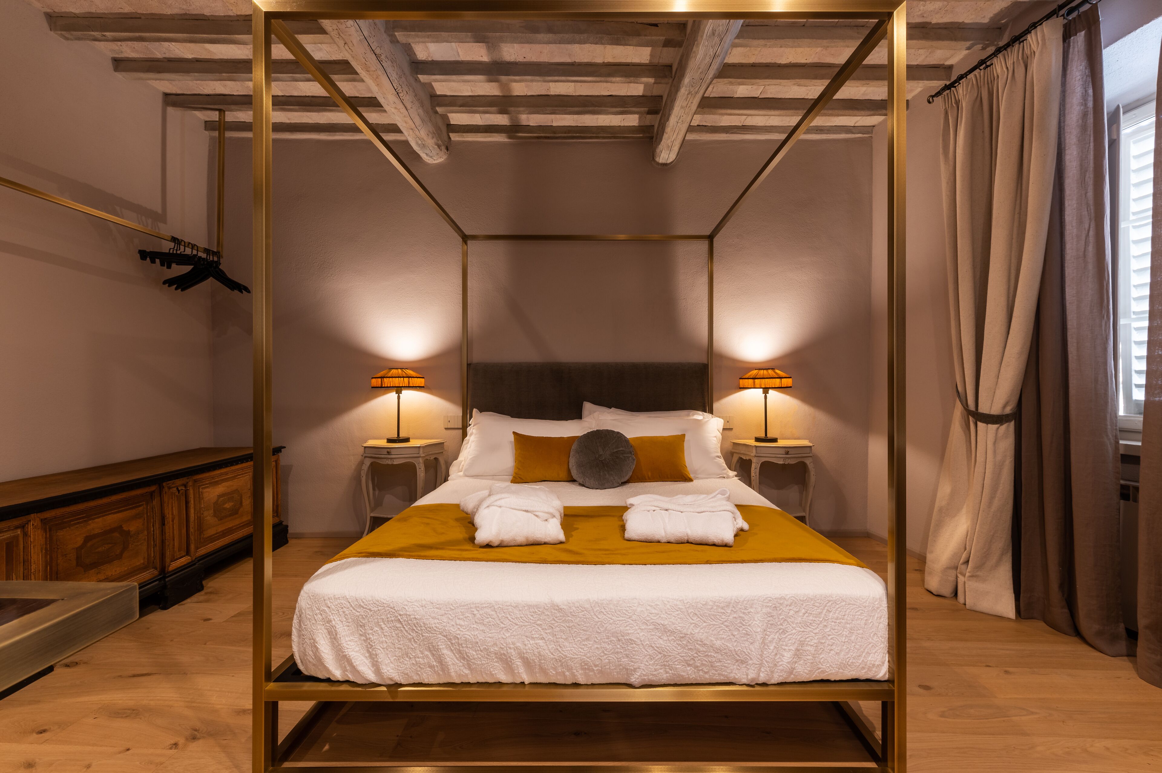 Una cama con dosel, ropa de cama blanca, dos lámparas de noche y un cabecero de madera.