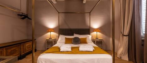 A four-poster bed with white linens, two bedside lamps, and a wooden headboard.