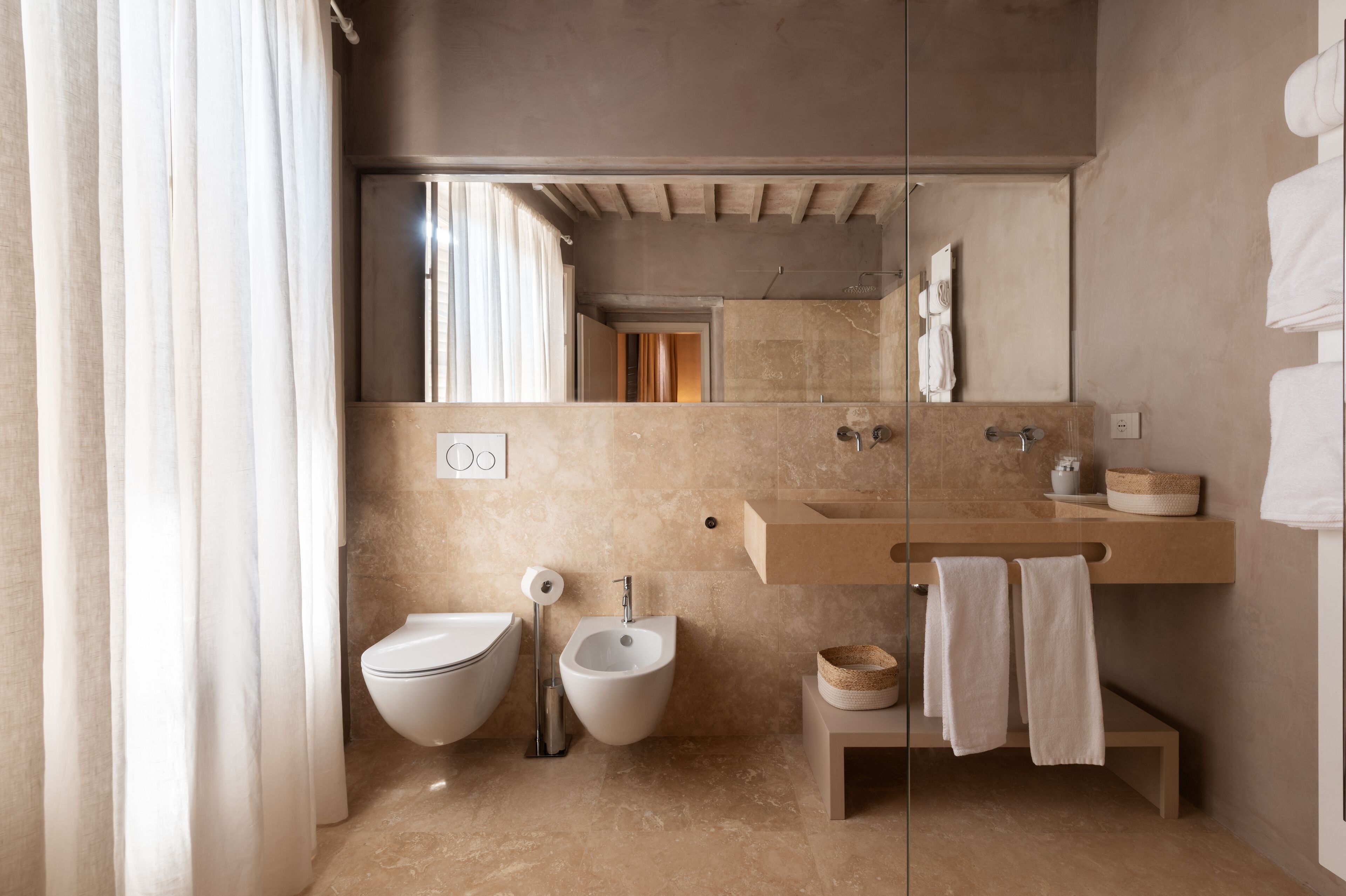 A modern bathroom with a bidet, a toilet, a sink, and a mirror.