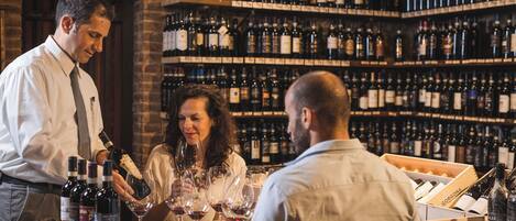 A bar with shelves of wine bottles and a table with wine glasses.