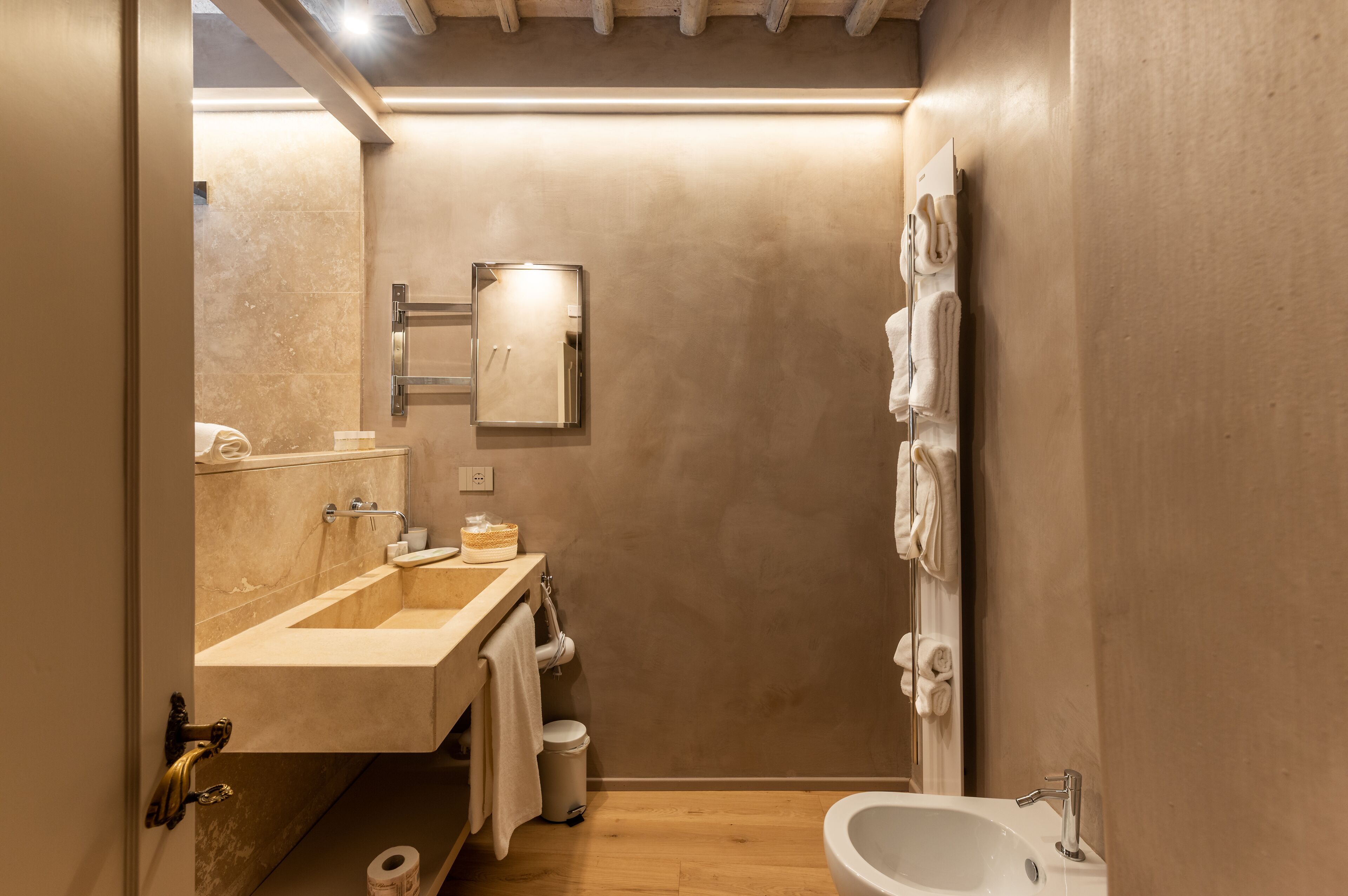 A modern bathroom with a sink, mirror, towel rack, and shower.
