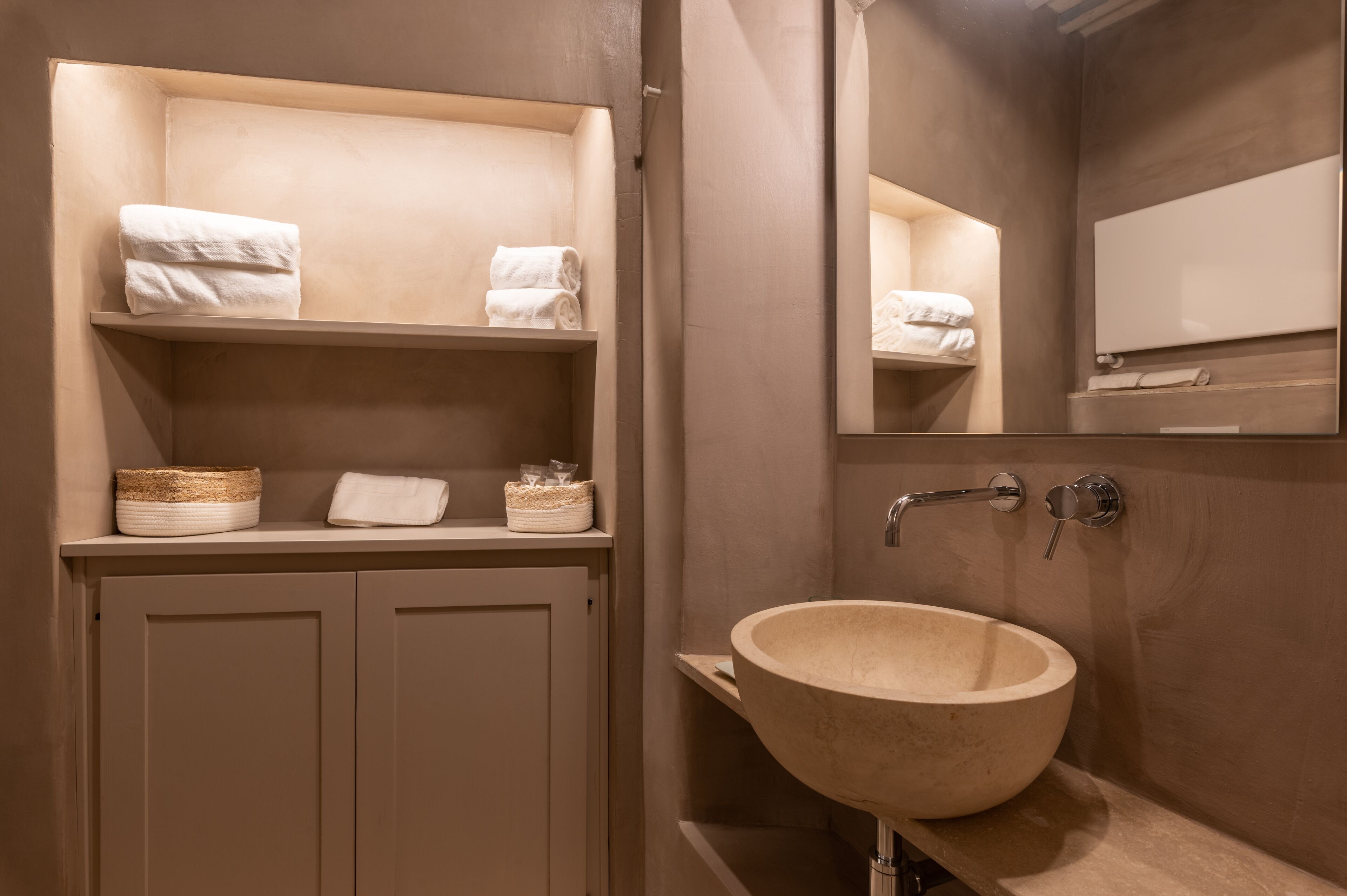A bathroom with a beige sink, two towel racks, and a mirror.