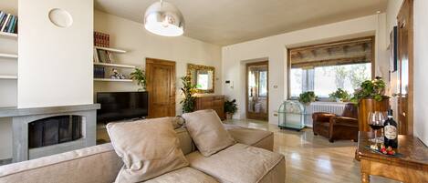 Una sala de estar con un sofá modular, una chimenea, un televisor y un comedor con una mesa y sillas de madera.