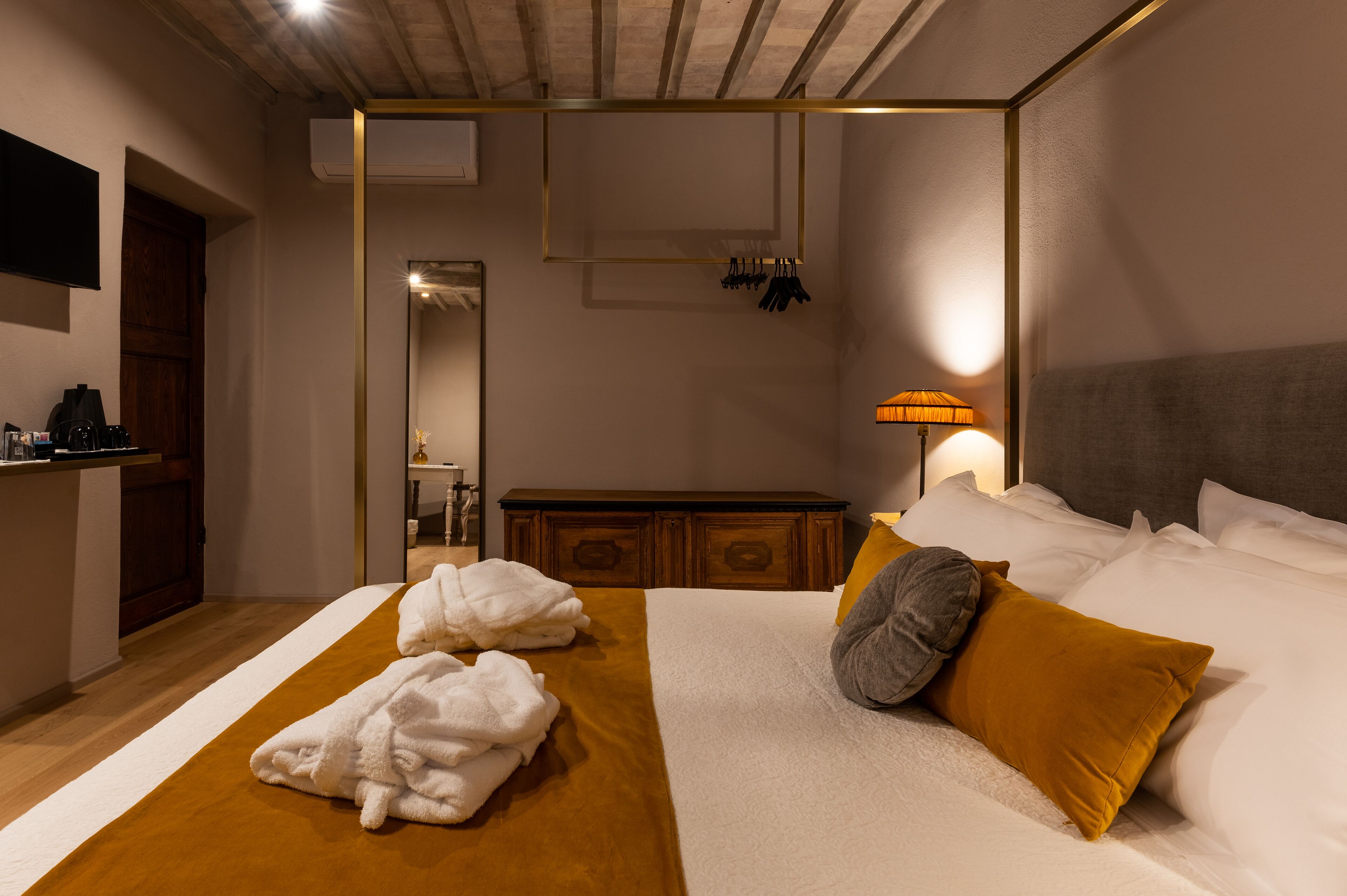 Habitació d'hotel amb un llit, un taulell de nit de fusta, un mirall i una làmpada.