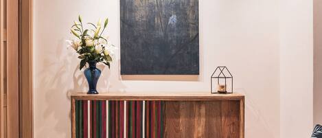 Una habitación con techo de madera, un cuadro en la pared, una consola con un florero y un sofá.