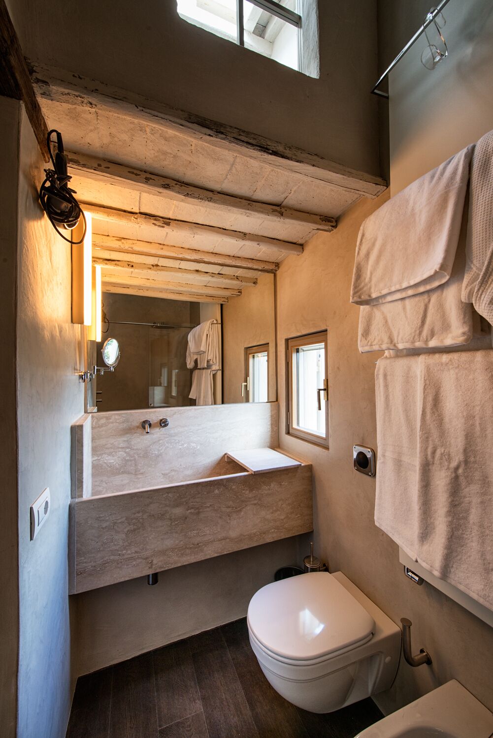 A compact bathroom with a wooden vanity, a white toilet, and a mirror.