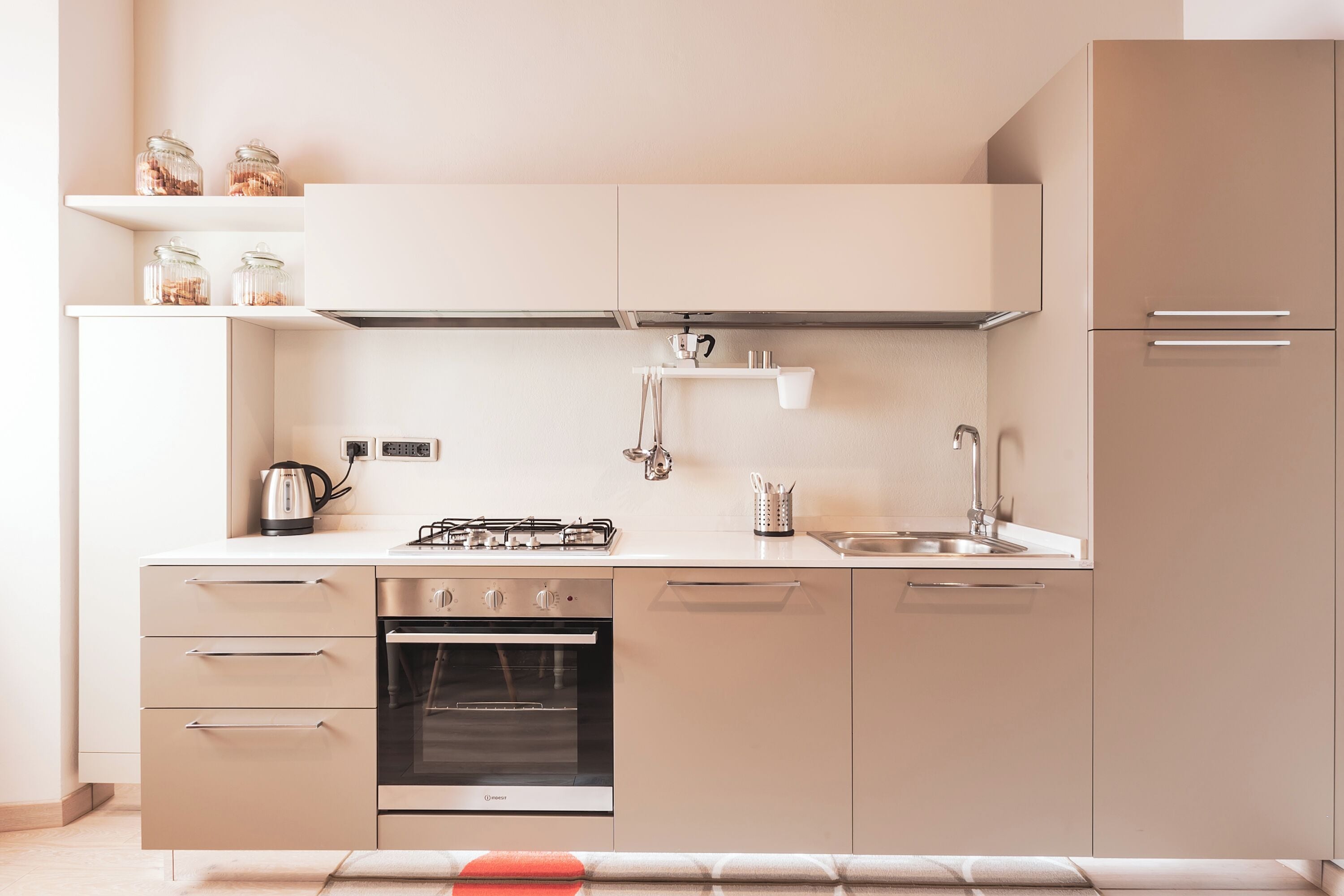 A modern kitchen with a gas stove, oven, sink, and stainless steel cabinets.