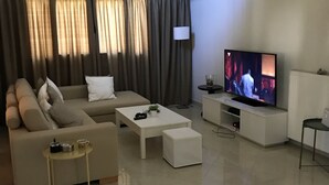 A modern living room with a sofa, coffee table, and TV. - Charming 2-bed House in Kallithea (Zakynthos)