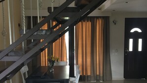 A dining area with a table and chairs, a staircase, and a door. - Charming 2-bed House in Kallithea (Zakynthos)