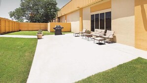 A patio with a barbecue grill, outdoor furniture, and a well-maintained lawn. - Motel6 Bartlesville OK (Bartlesville)