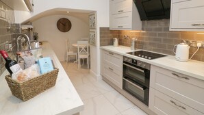 Una cocina moderna con horno empotrado, un comedor con mesa y sillas, y un reloj en la pared.