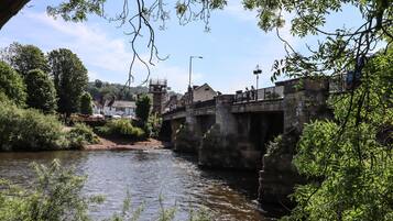 A stone bridge over a river with greenery on both sides.