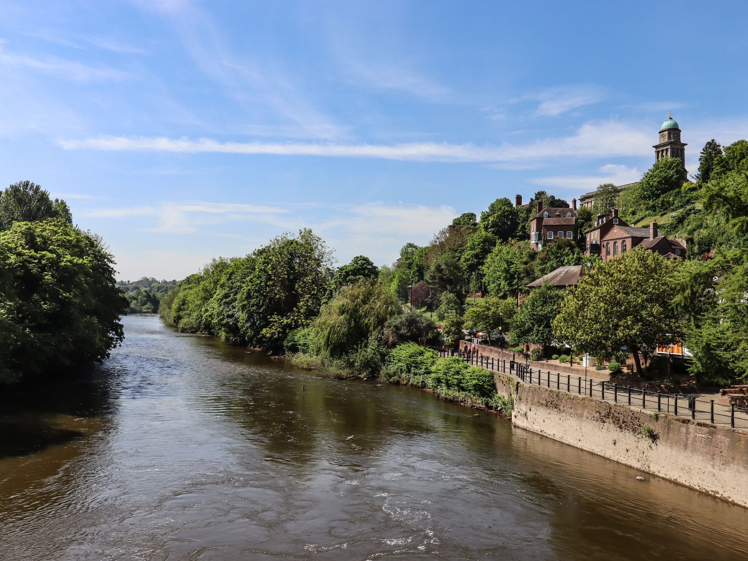 A river with a bridge, surrounded by lush greenery and historic buildings.
