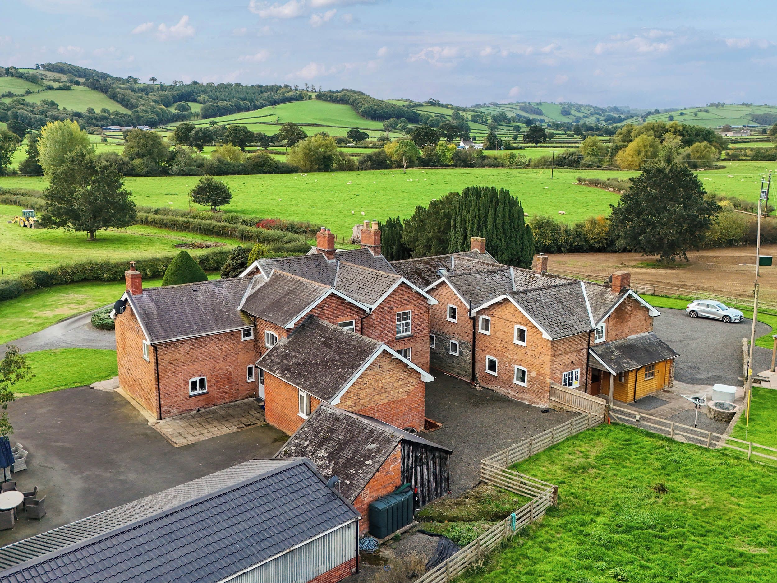 A cluster of traditional brick houses with a paved driveway and a fenced yard.