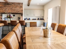 Comedor con mesa de madera, sillas de cuero y cubo para champán.
