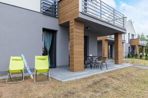 A modern building with a covered outdoor seating area, a balcony, and a grassy lawn. - Stylish Apartment with Terrace | Free Parking Space (Jastrzebia Góra)