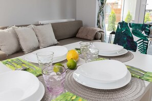 Una mesa con vajilla blanca, vasos y cubiertos, una lima y un limón sobre un protector de mesa tejido.