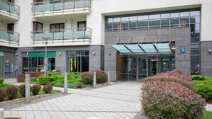 Un bâtiment moderne doté d’une entrée en verre, d’un auvent vert et d’un panneau indiquant une place de stationnement de catégorie 4A.