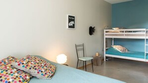 Une chambre avec un lit superposé, une chaise, un bureau et une lampe fixée au mur.