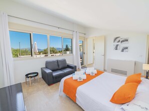 Une chambre d’hôtel avec un lit, un canapé, une petite table et une fenêtre donnant sur l’extérieur.