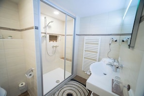 Une salle de bain moderne avec une douche à parois de verre, un lavabo blanc et un porte-serviettes.