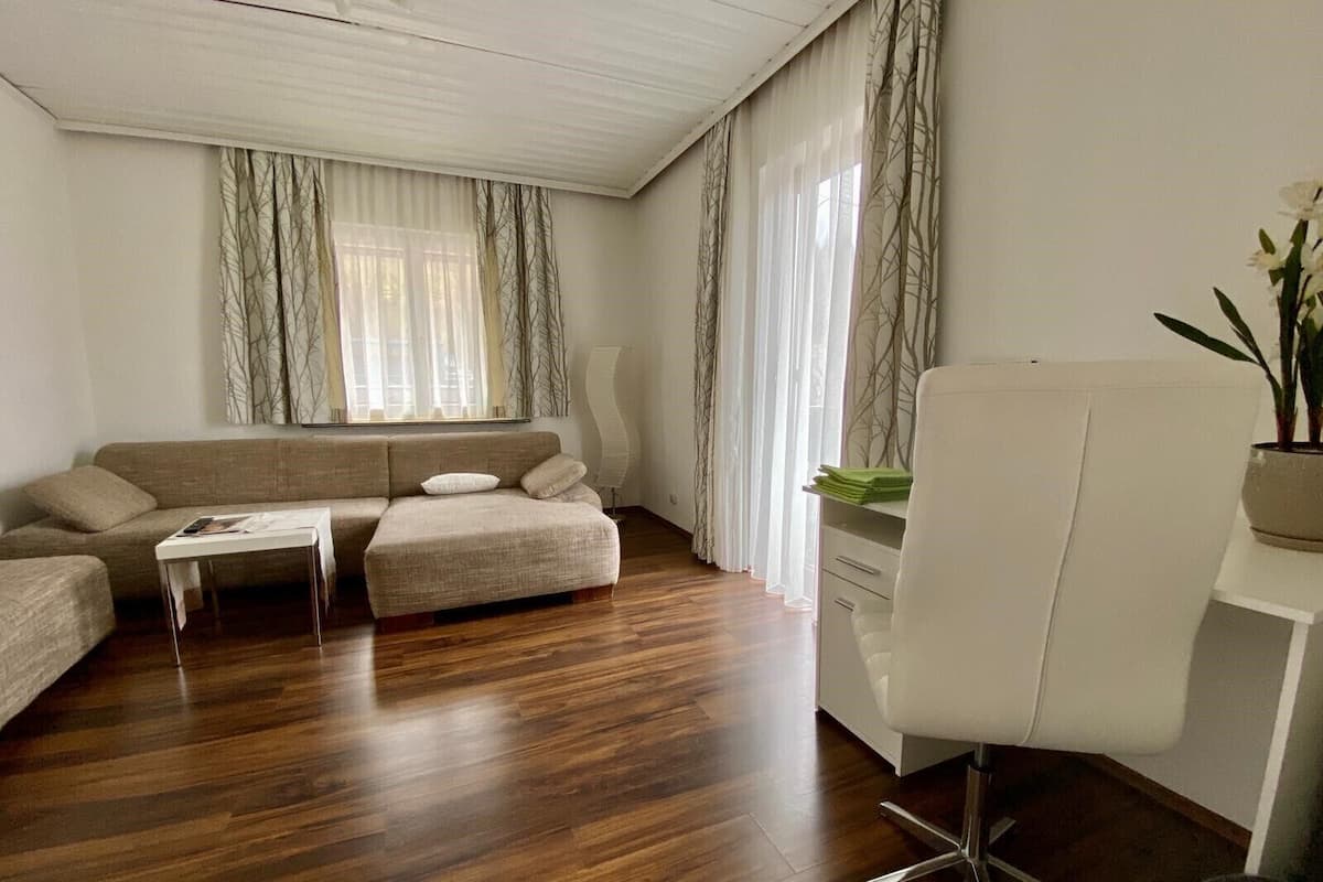 A modern living room with a sofa, ottoman, coffee table, and a white desk with a chair.