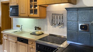 A kitchen with wooden cabinets, a microwave, a stove, and a sink. - Dormio Gasthof Höllwirt (Obertraun)