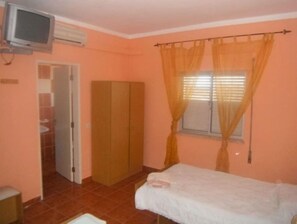Cozy retreat with a bed, wardrobe, and TV, offering a comfortable space to unwind.
