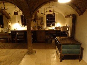 Une cuisine rustique avec des arches en briques apparentes, des meubles en bois et des ustensiles de cuisine suspendus.