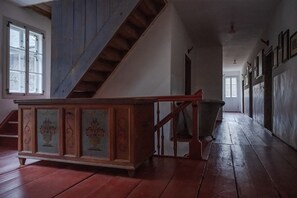 Un escalier en bois, doté d’une rampe, mène à un palier où se trouve un banc en bois.