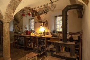 Une cuisine rustique avec un poêle à bois, des casseroles suspendues et une arche en pierre.
